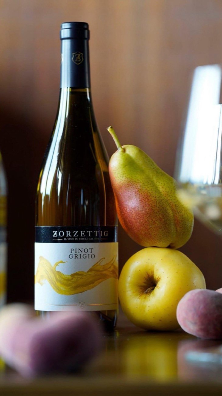 A Zorzettig white wine bottle beside pears and plums